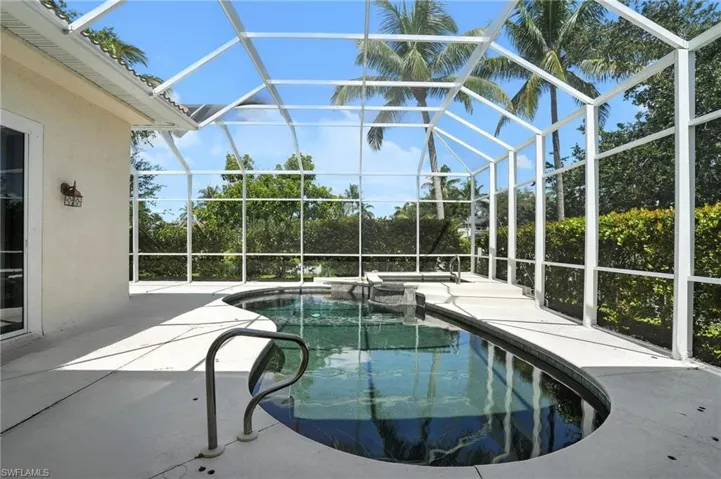 View of pool with a patio area, a lanai, and a pool with connected hot tub - Virtually Edited Image