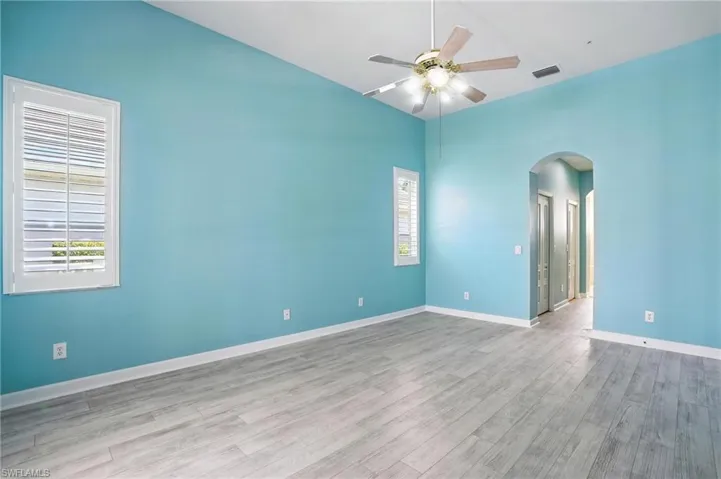 Primary Bedroom with arched walkways, plenty of natural light, a ceiling fan, wood finished floors, and high vaulted ceiling - Virtually Edited Image