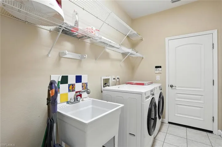 Laundry area featuring washer and clothes dryer and light tile patterned floors - Virtually Edited Image