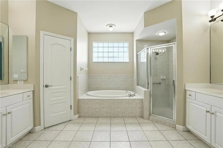 Bathroom featuring two vanities, a stall shower, and a bath - Virtually Edited Image