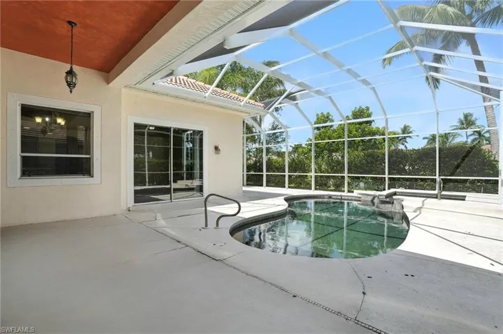 View of pool with a patio, glass enclosure, and a pool with connected hot tub - Virtually Edited Image