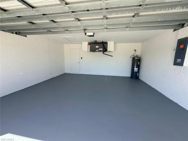 Garage featuring a textured wall, electric panel, and electric water heater