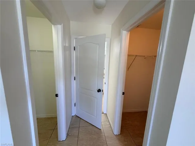 Hallway with light tile patterned floors and baseboards