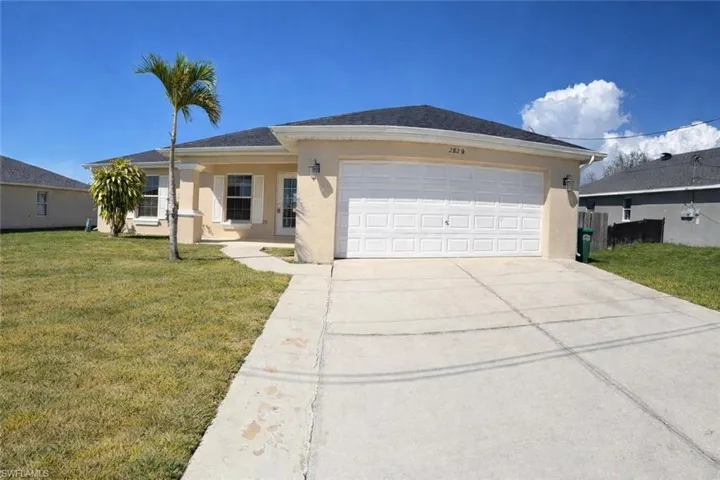 Ranch-style house with a front lawn, concrete driveway, stucco siding, and a garage