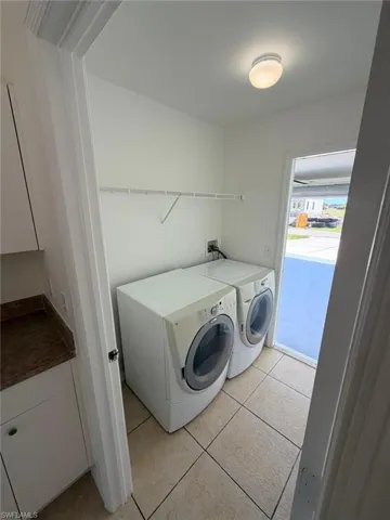 Laundry area with washing machine and dryer and light tile patterned floors