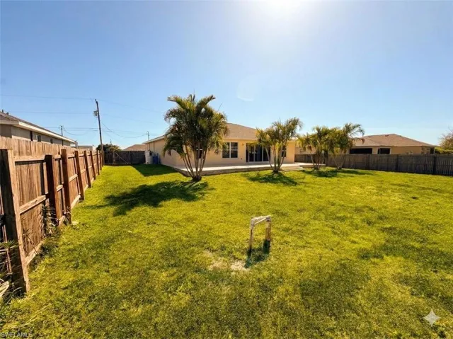 Rear view of property with a fenced backyard and a patio