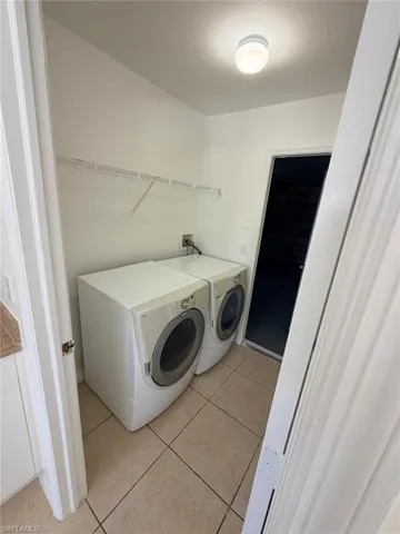 Laundry area featuring light tile patterned floors and independent washer and dryer