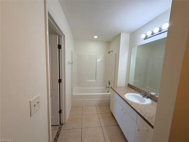 Full bathroom with vanity, light tile patterned floors, bathing tub / shower combination, and recessed lighting