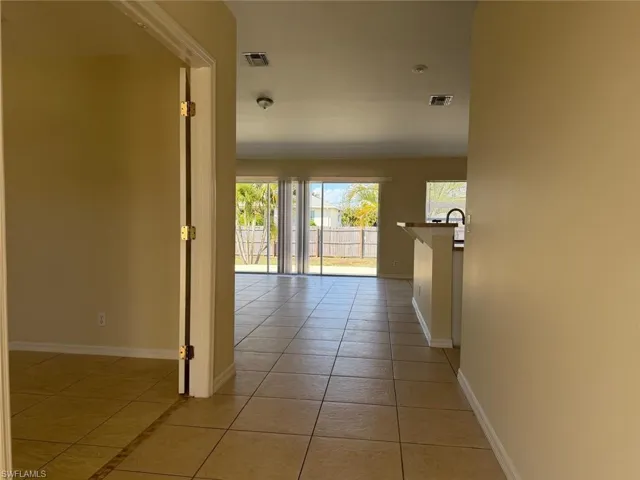 Hallway with light tile patterned floors and baseboards
