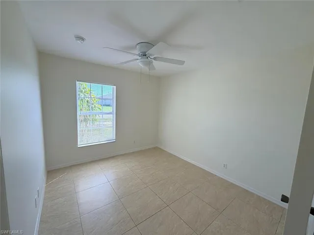 Spare room with a ceiling fan and light tile patterned floors