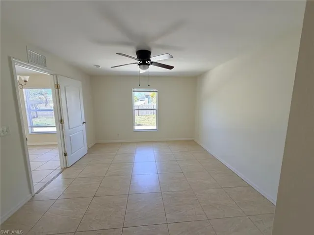 Empty room with a ceiling fan and light tile patterned floors