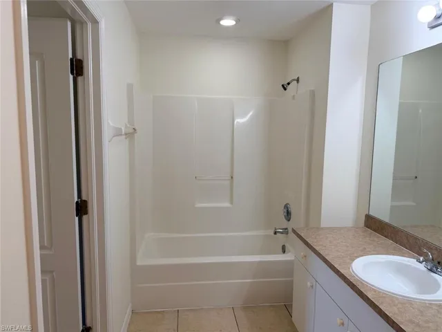 Bathroom with vanity, washtub / shower combination, and light tile patterned floors