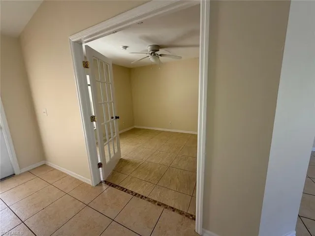 Hallway featuring light tile patterned floors and baseboards