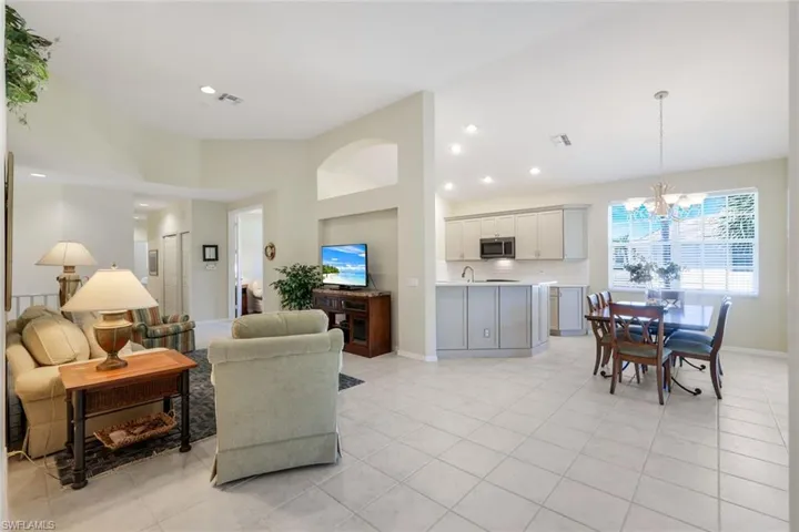 Living room featuring light tile patterned floors, baseboards, lofted ceiling, recessed lighting, and a notable chandelier
