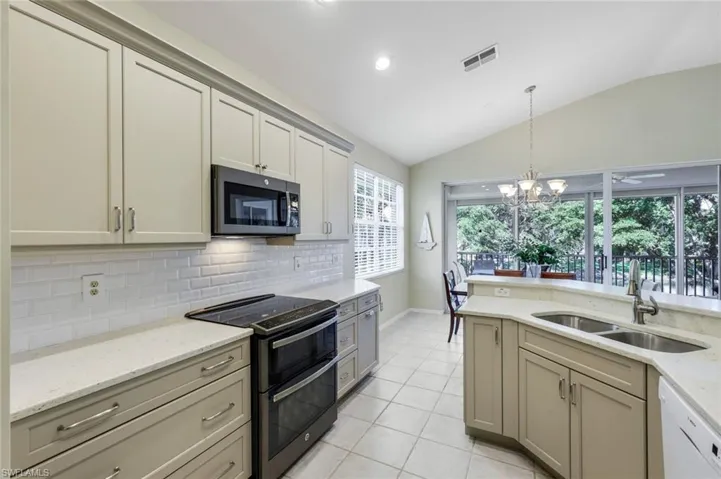 Kitchen featuring visible vents, dishwasher, vaulted ceiling, range with two ovens, and a sink