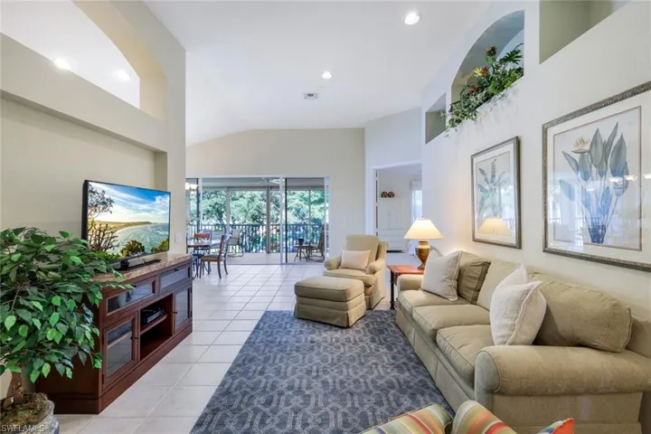 Living area featuring light tile patterned floors, visible vents, recessed lighting, and vaulted ceiling