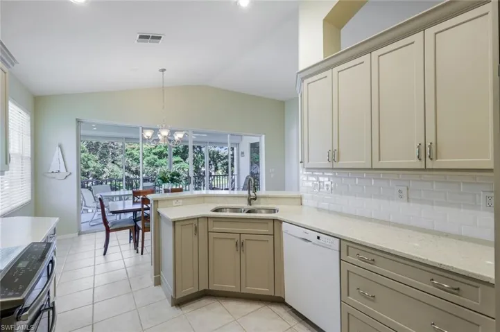 Kitchen featuring visible vents, a sink, vaulted ceiling, dishwasher, and tasteful backsplash