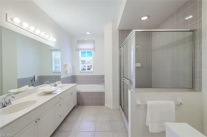 Full bathroom featuring tile patterned flooring, a stall shower, a garden tub, and a sink