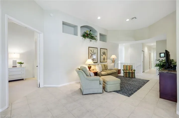 Living room featuring light tile patterned floors, baseboards, visible vents, a high ceiling, and recessed lighting