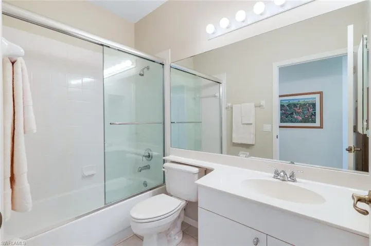 Full bath featuring tile patterned flooring, toilet, vanity, and bath / shower combo with glass door