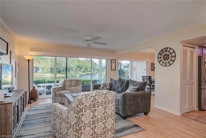 Living area with a water view, light wood-type flooring, a ceiling fan, and ornamental molding