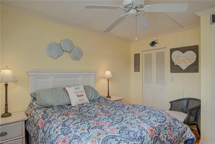 Bedroom featuring ornamental molding, a ceiling fan, a closet, and a textured ceiling