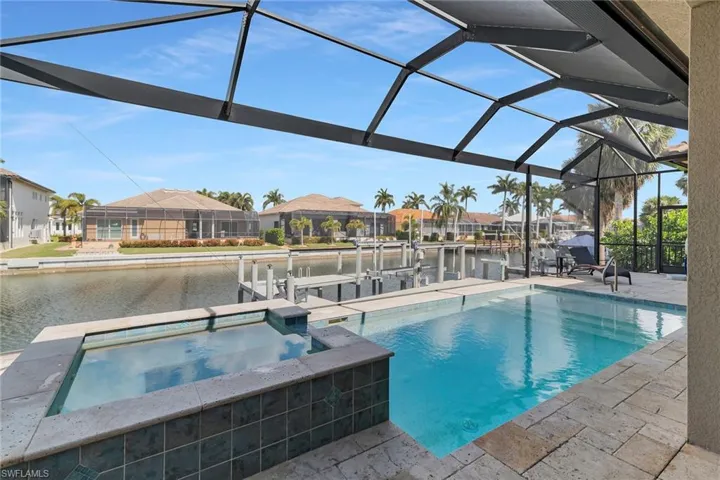 Integrated pool / spa with boat lift, a sunroom, a water view, a residential view, and a dock