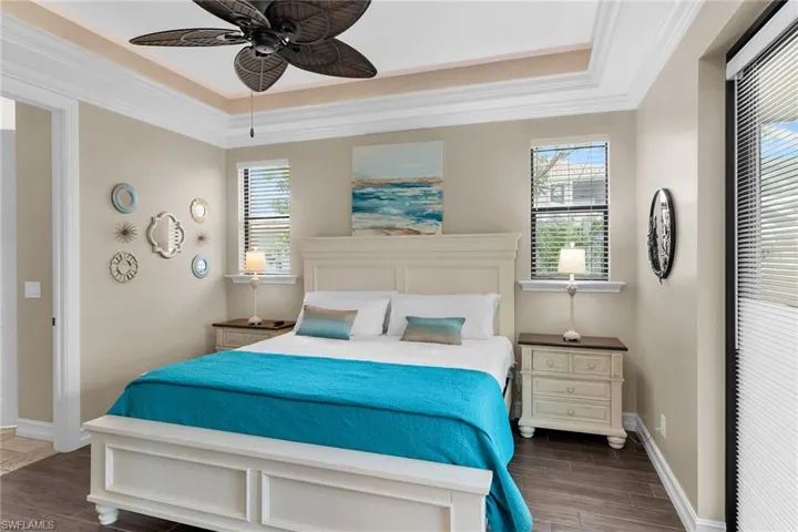 Bedroom with wood tiled floors, a ceiling fan, and crown molding