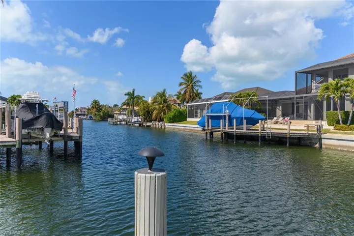 Dock featuring boat lift, a sunroom, and a water view