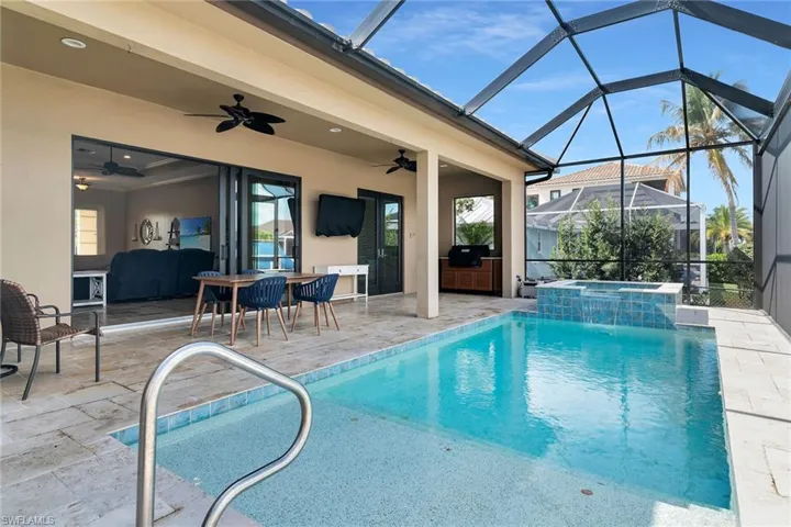 Combined pool / hot tub featuring outdoor dining area, a patio, a sunroom, and glass enclosure