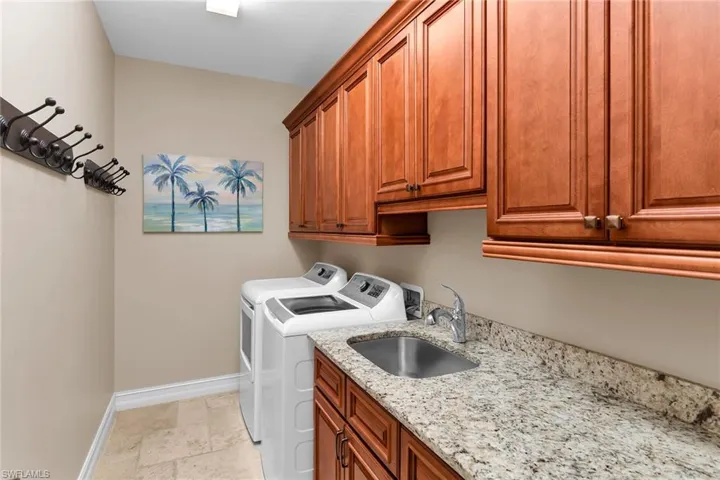 Laundry area with stone tile floors, cabinet space, and independent washer and dryer