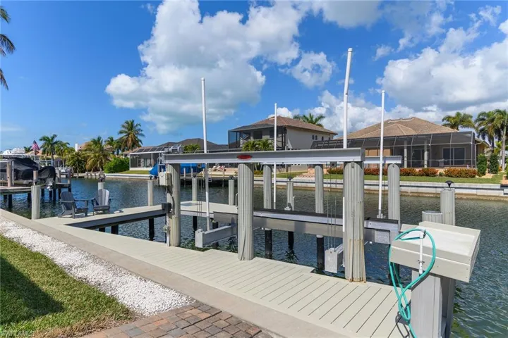 Dock with boat lift, a water view, and a sunroom