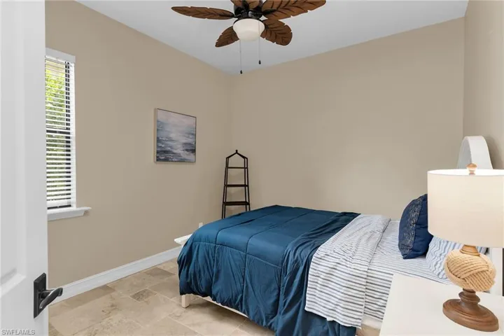 Bedroom featuring multiple windows, a ceiling fan, and stone finish floors