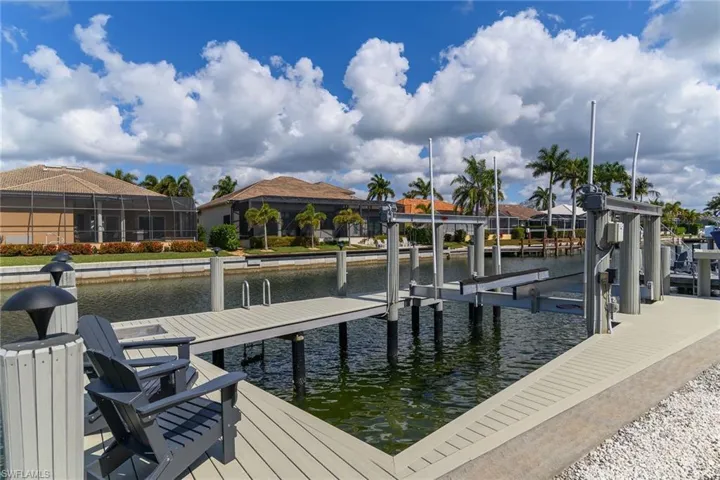 Dock area with boat lift, a water view, and a residential view
