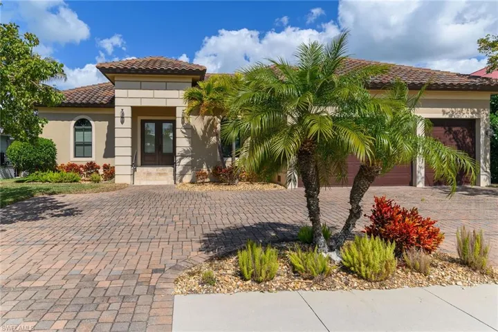 View of front facade with french doors, a tile roof, stucco siding, decorative driveway, and an attached garage