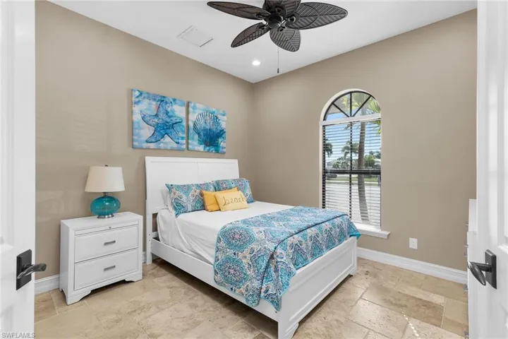 Bedroom with stone tile floors, ceiling fan, and recessed lighting