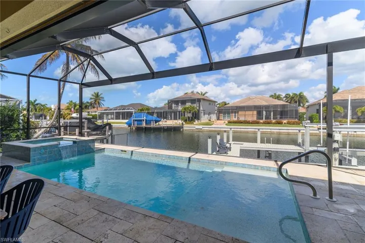 Combined pool / hot tub featuring a sunroom, a water view, a residential view, a patio, and a lanai
