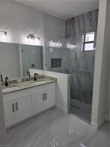 Bathroom featuring double vanity and a marble finish shower