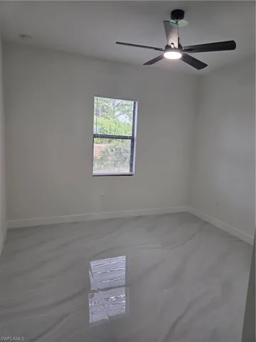 Empty room with baseboards and a ceiling fan