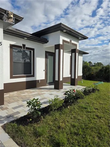 Property entrance with a patio, stucco siding, and a yard