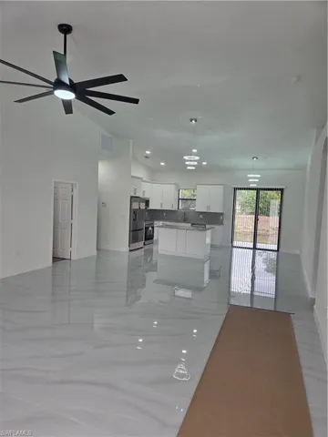 Kitchen with open floor plan, white cabinetry, hanging light fixtures, and a center island