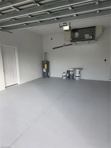 Garage with water heater, a textured wall, and a garage door opener