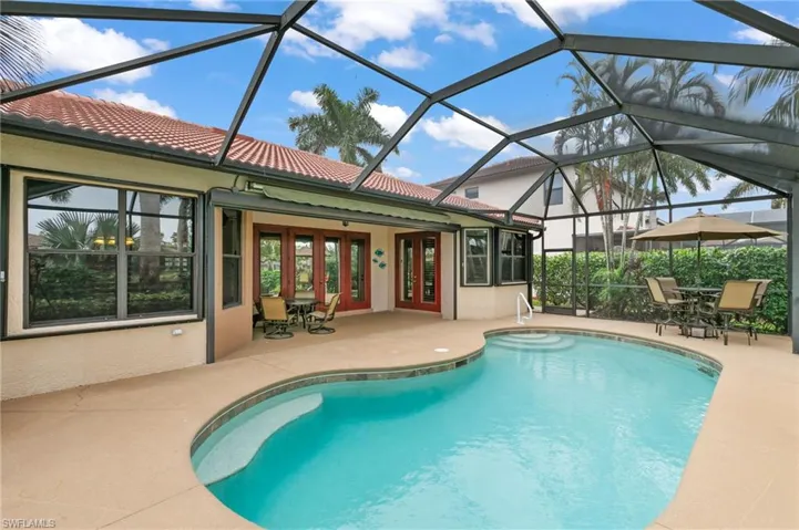 View of pool featuring glass enclosure, ceiling fan, french doors, and a patio area