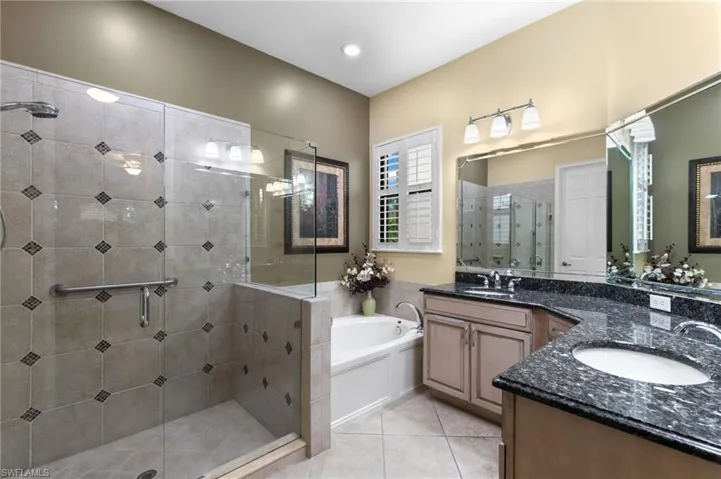 Bathroom featuring tile patterned floors, vanity, and separate shower and tub