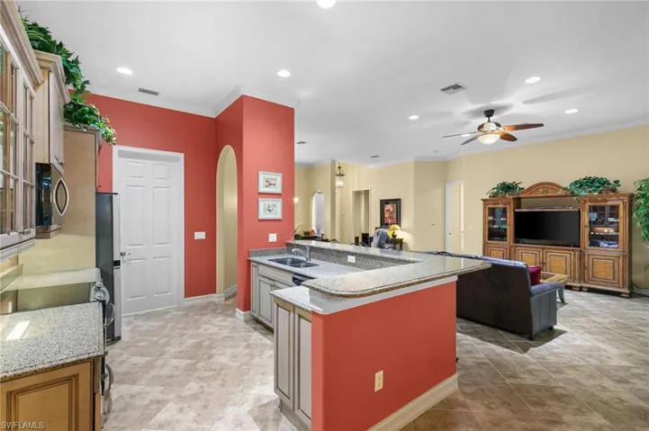 Kitchen with sink, appliances with stainless steel finishes, crown molding, light stone countertops, and ceiling fan