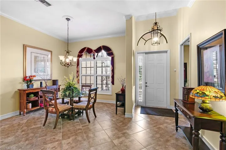 Foyer with crown molding, a chandelier, and a wealth of natural light