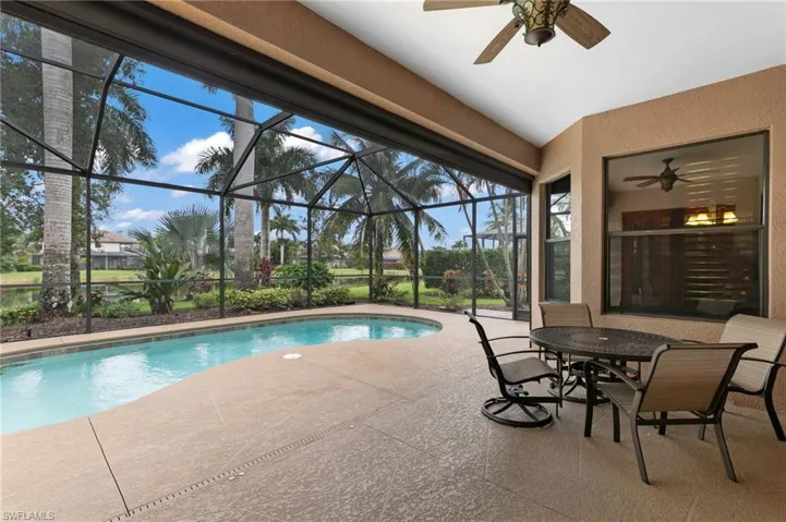 View of swimming pool featuring ceiling fan, glass enclosure, and a patio area