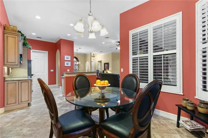 Tiled dining area with ceiling fan with notable chandelier and crown molding