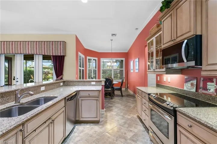Kitchen with appliances with stainless steel finishes, light stone countertops, ornamental molding, and sink