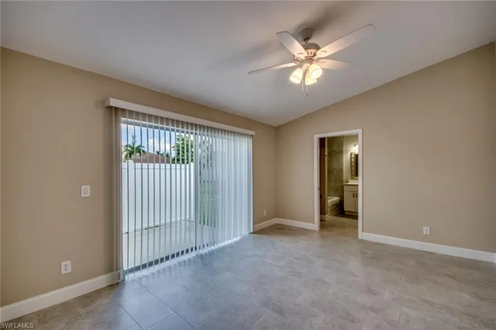 Tiled empty room featuring ceiling fan and vaulted ceiling
